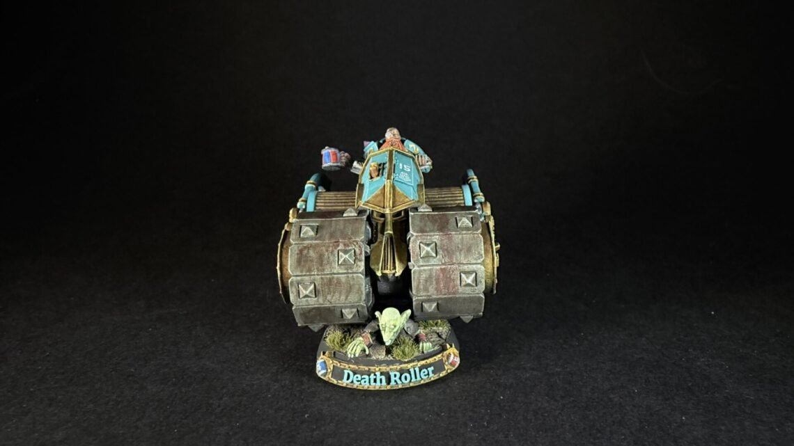 Front view of a painted Death Roller miniature war machine with teal cockpit, armored wheels, and goblin crew on a round base.